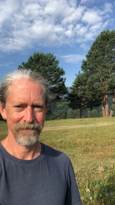 Photo of Stewart in a field with pine trees